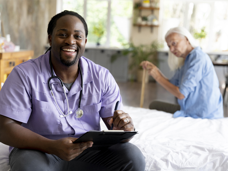 Male nurse assisting an elderly patient at home.