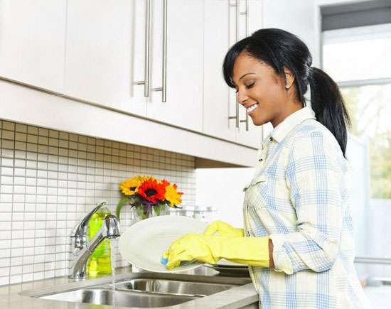 A caregiver washing dishes as part of homemaking services to maintain a clean and tidy home.