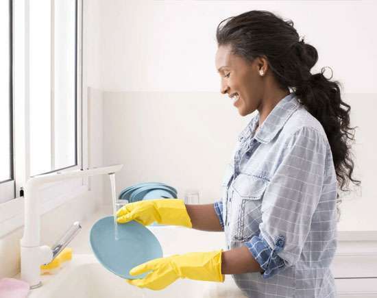 A caregiver washing dishes as part of senior house cleaning services, helping seniors maintain a clean and healthy home environment.