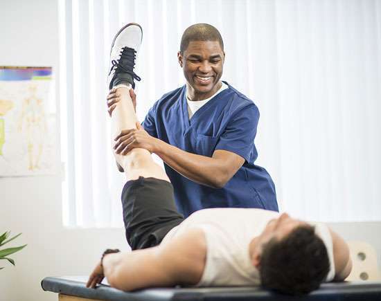 Healthcare professional providing mobility assistance to a senior patient in a daily living support service setting.